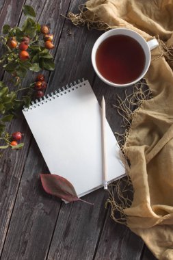 Sonbahar flatlay bir fincan çay ve düşmüş kuru sarı ile ahşap zemin üzerinde kırmızı yaprakları, çiçekleri. Metin için özgür yer. Rahat ev concept