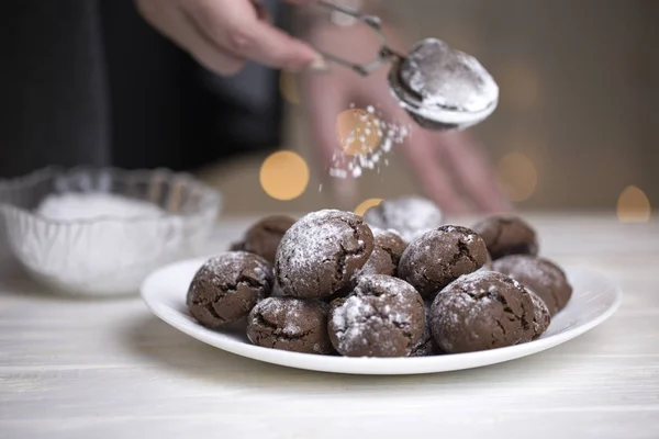 sifting powdered sugar on the top. Sprinkling powdered sugar on chocolate cookies crinkles. chocolate cookies with powdered sugar