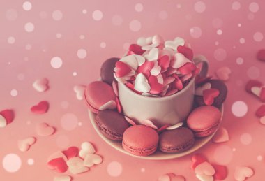 Küçük kalpler ve macaroons için Sevgililer günü geçmiş yumuşak bokeh ışıklı pembe arka plan üzerinde fincanla. Vintage tarzı.
