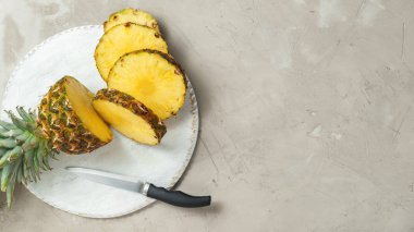 Bir beyaz tahta kesme tahtası üzerinde taze dilimlenmiş ananas. Beton tablo artalanları. Üstten Görünüm, sizin metin için yer