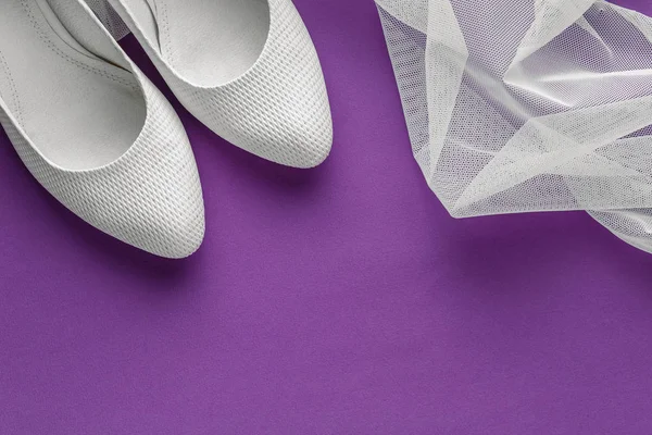 紫色の背景にベールを持つ白の結婚式の靴 — ストック写真