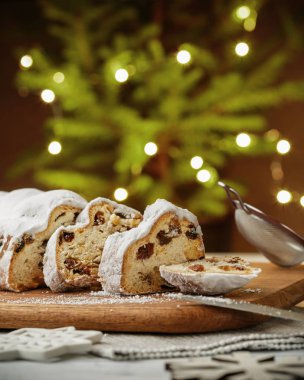 Stollen, geleneksel Alman Noeli Maya kek üzümlü masada, köknar ağacı bokeh arka plan üzerinde ışıklar