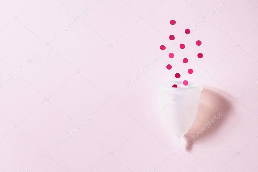 Menstrual cup on pink background. Alternative environmentally friendly feminine hygiene product to collect blood during the period inside the vagina. Women health concept
