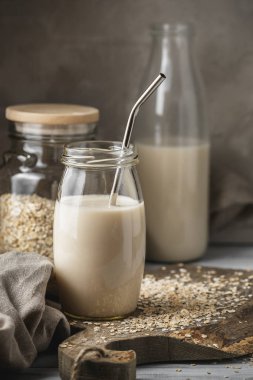 Sigara süt yulaf süt cam ile saman rustik özgeçmişlerine içme metal yeniden kullanılabilir. Masanın üzerine dağılmış yulaf gevreği.