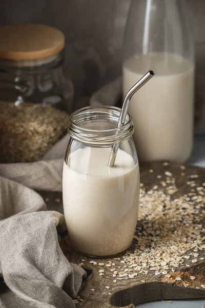 Sigara süt yulaf süt cam ile saman rustik özgeçmişlerine içme metal yeniden kullanılabilir. Masanın üzerine dağılmış yulaf gevreği.