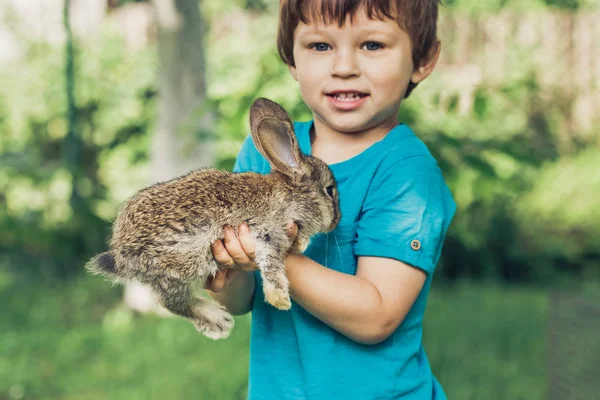 Le petit garçon tient un lapin à la ferme — Photo