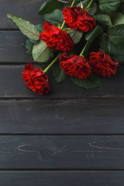 Siyah ahşap arka plan üzerinde kırmızı gül çiçekler