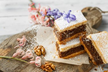 Ev yapımı cevizli turta. Şekerli kremalı. Parçalara ayırıp yemeye hazır. Tahtada servis edilen tatlı.