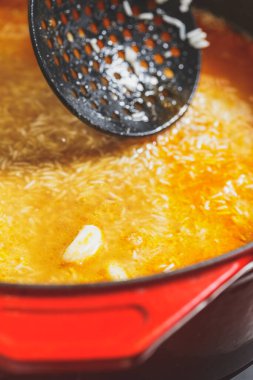 Kırmızı kazanda kuzu eti ve pilav pilavı pişiriliyor.