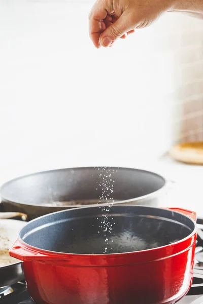 Мужская Рука Добавляет Соль Время Приготовления Пищи Красной Эмалированной Чугунной — стоковое фото