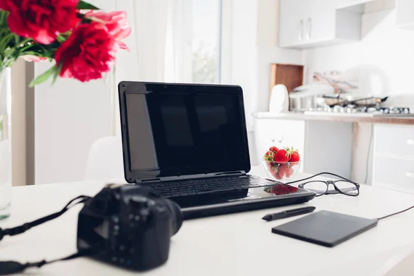 空工作区的自由职业者摄影师在厨房 使用笔记本电脑 照相机和钢笔片在家工作 — 图库照片