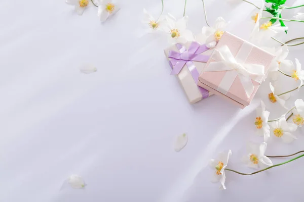 Gift boxes with white flowers on white background. Morning surprise. Copy space
