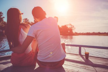 Mutlu çift aşık nehirde sarılma günbatımında rıhtım. Genç insanlar tarafından manzarayı su soğutma