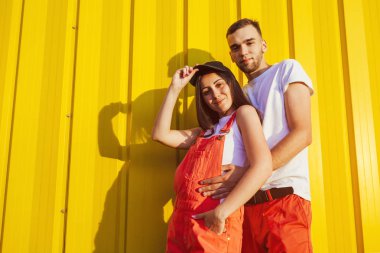 Mutlu çift sarı duvara günbatımında sarılma aşık. Gülümseyen genç hipsters. Uzay