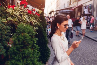 Genç kadın turist yolu eski şehirde bulmak için onun smartphone kullanarak. Yaz tatili