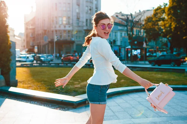 Young excited woman wearing stylish outfit outdoors. Happy girl jumping and having fun. Beauty fashion concept