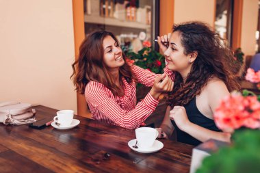 Yaz aylarında açık kafede kahve yaparken makyaj yaparken mutlu arkadaşlar. Asılı ve having fun kadınlar