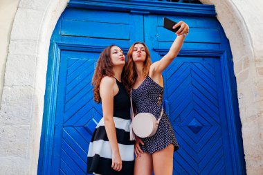 Eski şehrin sokaklarında yürürken smartphone kullanarak selfie alarak mutlu arkadaşlar. Eğleniyor kadınlar