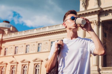 Yakışıklı üniversitelim üniversitenin karşı kahve içme. Adam öğrenci sınıfları sonra rahatlatıcı sırt çantası ile. Yaşam tarzı