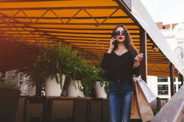 Güzel şık genç kadınla poşetler kafe dışında şehir caddede yürüyüş ve Evet. Moda kavramı