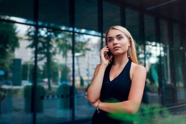 Genç Sarışın işkadını cam iş merkezi City tarafından Smartphone kullanarak arama. İş, müşteri ile iletişim teknolojisi ve kariyer kavramı