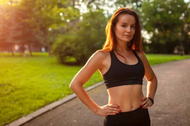 Kameraya egzersiz yaptıktan sonra yaz parkta arayan genç sportif kadın. Spor giyim. Güçlü kadın dinlenme. Sağlıklı yaşam tarzı
