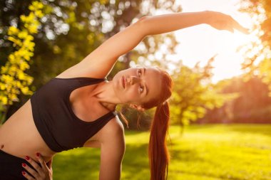 Genç sportif kadın yaz Park yapıyor. Vücudu germe sporcumuz. Egzersiz