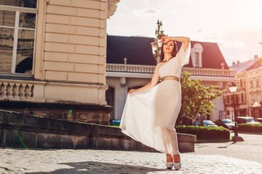 Beyaz gelinlik içinde açık havada yürüyen güzel kadın. Tek omuzlu elbise aksesuarları ve mücevher. Moda kavramı