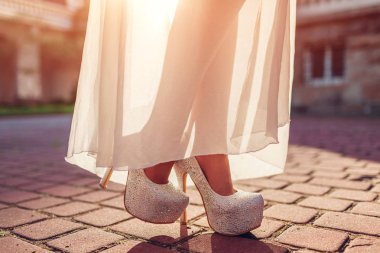 Açık havada yüksek topuklu ayakkabı ve beyaz elbise giymiş şık kadın. Güzellik moda. Ayakkabı