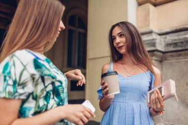 İçme kahve konuşmak iki genç güzel kadın. Kızlar şehirde eğleniyor. En iyi arkadaşlar açık havada sohbet. Üniversiteli gençler