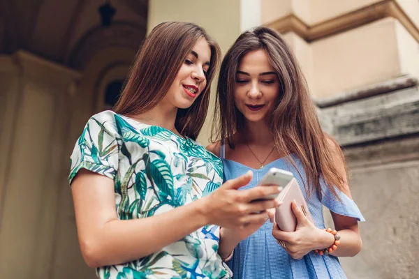 Açık havada Smartphone kullanarak iki genç güzel kadın. Sosyal ağ şehir sokak üzerinde kontrol kızlar. Arkadaşlarım birlikte asılı