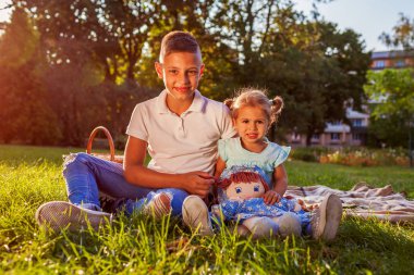 Yürümeye başlayan çocuk kardeşi park ve sarılma ile çimlerde oturan çocuk. Mutlu bir aile pikniği. Aile değerleri