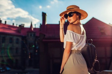 Şapka ve güneş gözlüğü açık havada giyen genç şık kadın. Sırt çantası ve retro kıyafeti giymiş Lviv içinde yürümek telefon ile şık kız
