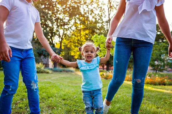 Parkta oynarken mutlu aile harcama zaman açık havada. Anne iki çocuk ile eğleniyor. Yürüyüş ve elele yürümeye başlayan çocuk ile. Aile değerleri