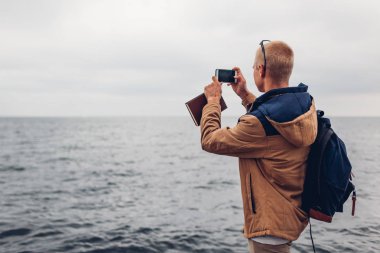 Sırt çantası ve kitap alarak resmi telefon kullanarak ve Odessa plajda manzaranın deniz ile üniversite öğrencisi. Kumsalda yürüyen turist