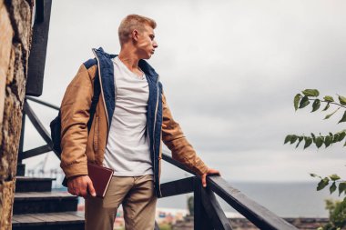 Sırt çantası ve deniz manzaralı Odessa'daki hayran kitap üniversite öğrencisi yağmurlu günde şehirde yürüyüş