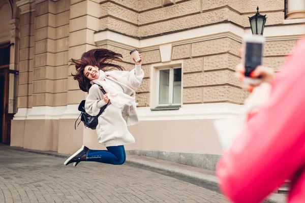 Kadın turistler bardak kahve ile Odessa opera house tarafından atlama onun arkadaşı resim çekmek. Mutlu arkadaş yolcuları eğleniyor