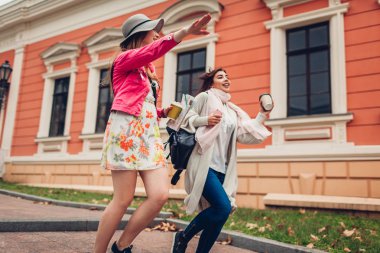 Bir taksi Odessa'daki bardak kahve ve harita ile çalışan iki kadın turist. Mutlu arkadaş yolcuları acele süre gülüyor