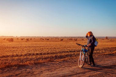 Genç bisikletçi alanında gün batımında at binme