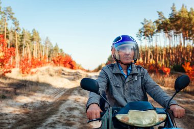 Komuta sizde binme scooter sonbahar orman yolu üzerinde. Sürücü motosiklet sürme kask içinde. Aktif yaşam tarzı