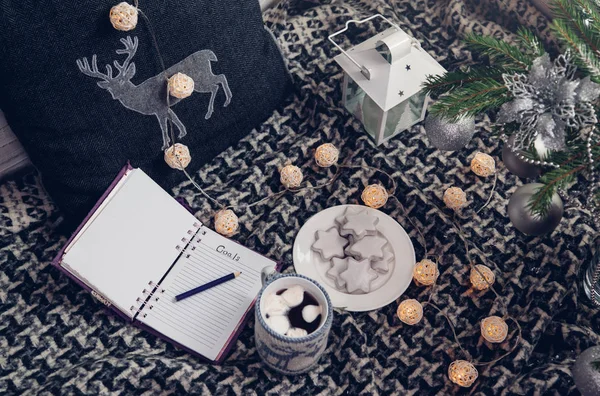 Writing goals for the next year with a cup of chocolate and biscuits under the Christmas tree