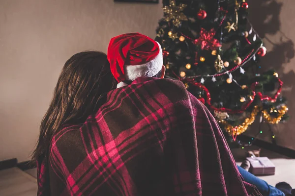 Verliebte Paare Sitzen Neben Einem Weihnachtsbaum Tragen Weihnachtsmützen Und Umarmen — Stockfoto