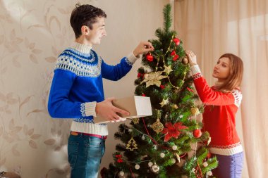 Çift evde, oyuncaklar ile Noel ağacı kış kazak giyen dekorasyon aşık. Yeni yıl için hazırlanıyor