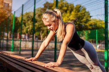 Genç kadın atlet şınav üzerinde sportsground yaz aylarında. Sağlıklı bir yaşam tarzı. Motivasyon