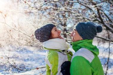 Kar fırlatma ve kış ormanda sarılma aşık çift. Gençler eğleniyor tatillerinde