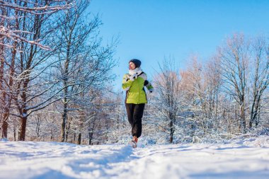 Sporcu kadın kış ormanda Sprint koşma. Soğuk karlı havalarda eğitim dışında. Sportif yaşam tarzı
