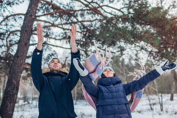 Beautiful loving couple throwing snow up in winter forest. happy people having fun outdoors. Winter activities