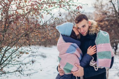 Çok güzel iki yürüyor ve kış ormanda sarılma sevgi dolu. İnsanlar ısınma battaniye ile örtülü. Kadın erkek arkadaşının yanağını öper