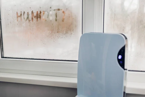 Islak penceresinde düz dokunmatik panel çalışmaları ile dehumidifier. Nem pencere üzerinde yazılı. Yüksek nem kavramı.