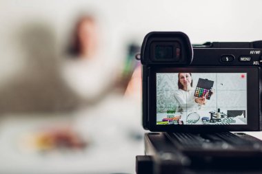 Genç kadın profesyonel güzellik vlogger veya blogger kayıt makyaj eğitimi kamera ve tripod evde kullanma
